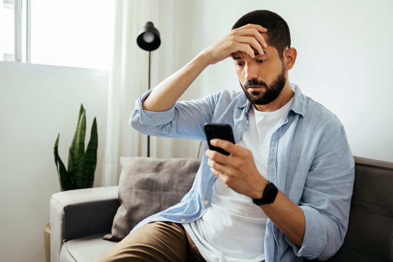 homme-triste-verifie-smartphone